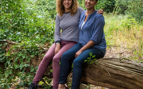 Juliet and Amy sit together on a fallen tree